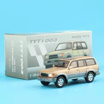 A 1/6 scale model toy car of a Mazda Tribute SUV, shown in front of its original gray packaging box on a solid light blue background.