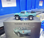 A teal RC toy truck with a mounted gun barrel, displayed on top of its gray packaging box which features the brand 'MASSDI' and 'TOYOTA' text.