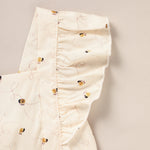 Folded cream-colored fabric with small black and yellow bee pattern on a beige background