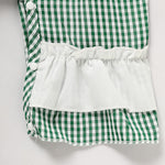 Green and white checkered outfit with a white ruffled top on a light gray background