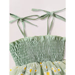 Green dress with floral pattern and ribbon straps on a light background