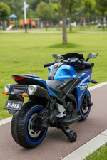 Blue electric toy motorcycle for kids with training wheels on a park pathway.