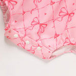 Pink baby romper with bow pattern on a white background