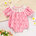 Pink baby romper with 'Daddy's Girl' text on a light background with flowers.