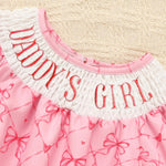 Pink dress with 'Daddy's Girl' text on a textured beige background