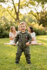 Toddler boy wearing an army green pilot jumpsuit for a special occasion
