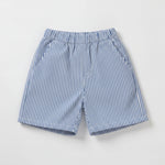Children's outfit with white t-shirt and blue shorts on a wooden surface with teddy bears.