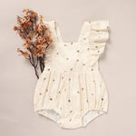 White baby romper with floral patterns on a beige background